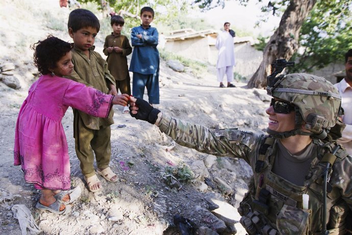 Una soldado da un caramelo a un niño en Afganistán