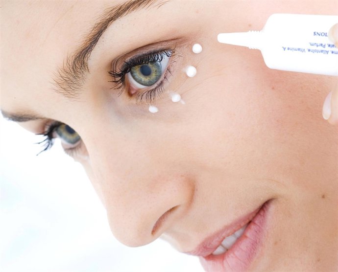 Mujer aplicandose crema antiarrugas en el contorno de ojos 