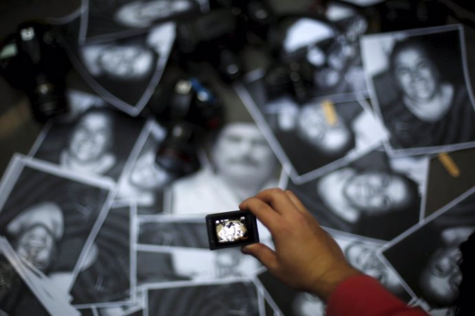 A woman takes photos of images of murdered journalists during a demonstration ag