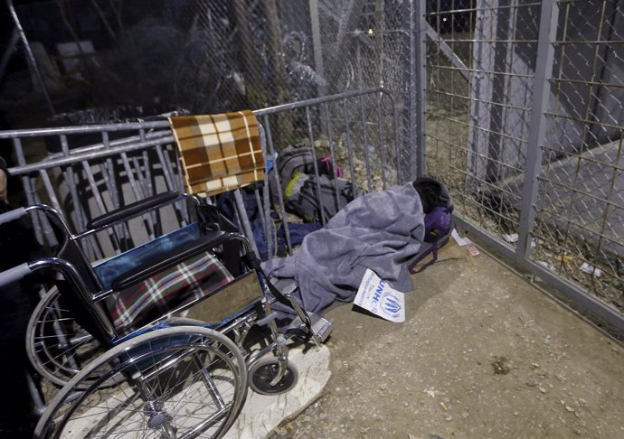 Una refugiada iraquí en silla de ruedas espera para cruzar de Grecia a Maceconia