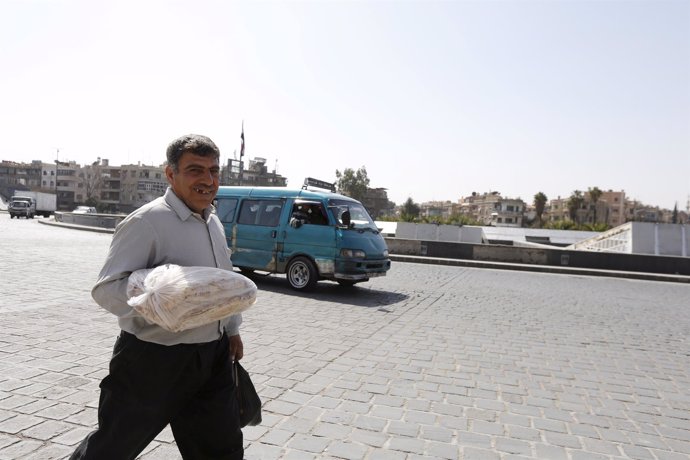 Ciudadano sirio lleva una barra de pan