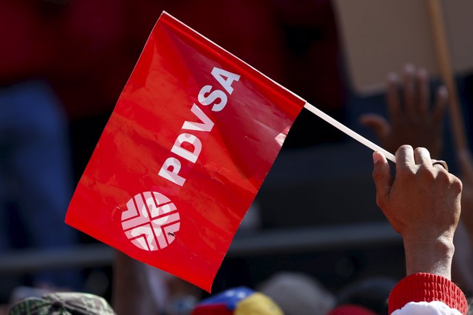 A worker of the Venezuelan state oil company PDVSA holds a flag with the company