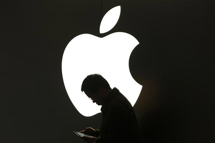 Un hombre revisa su iPad frente a un logo de Apple en las afueras de una tienda 