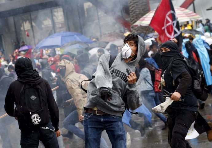 Demonstrators throw stones during clashes with riot police during a march to mar