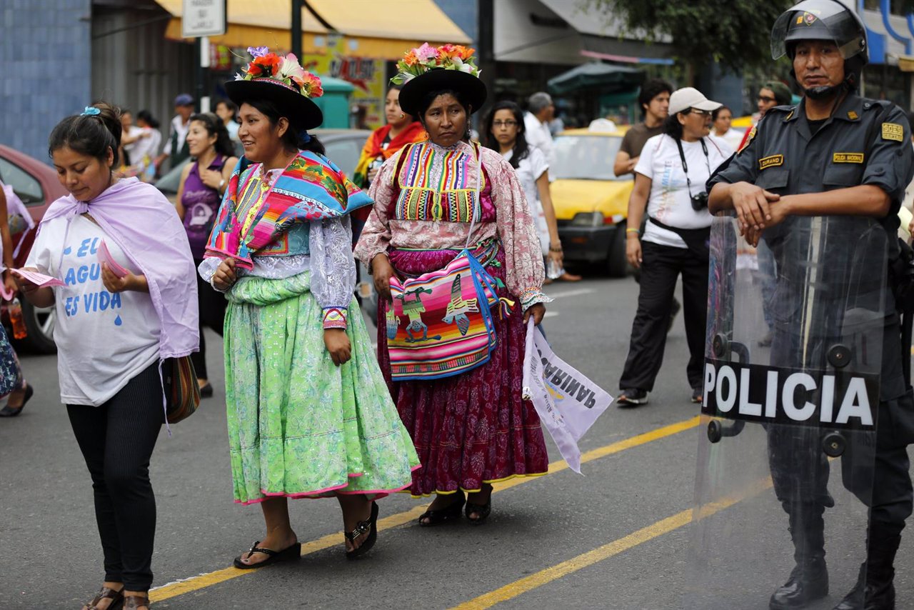 Peruvian women march next to a police officer during a celebration of Internatio