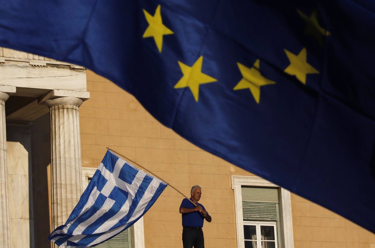 A protester waves a Greek flag at the entrance of the parliament building during
