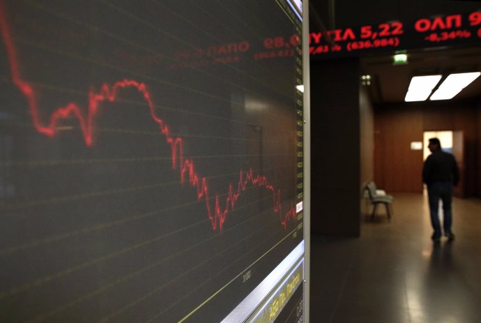A man walks inside Athens stock exchange as a monitor shows the general index
