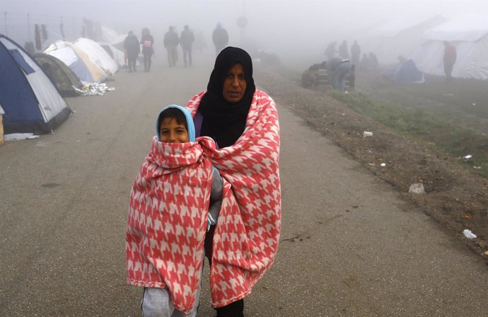 Una mujer inmigrante y su hijo esperan en Idomeni a cruzar hacia Macedonia