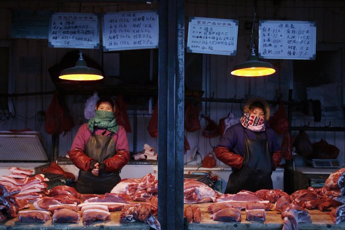 Pork vendors wait for customers at a market in Beijing