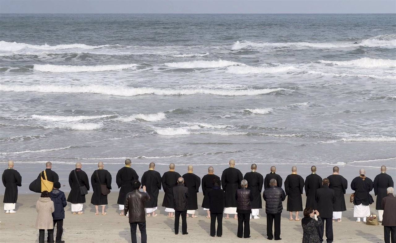 Familiares rezan junto con monjes budistas enfrente del mar de Japón