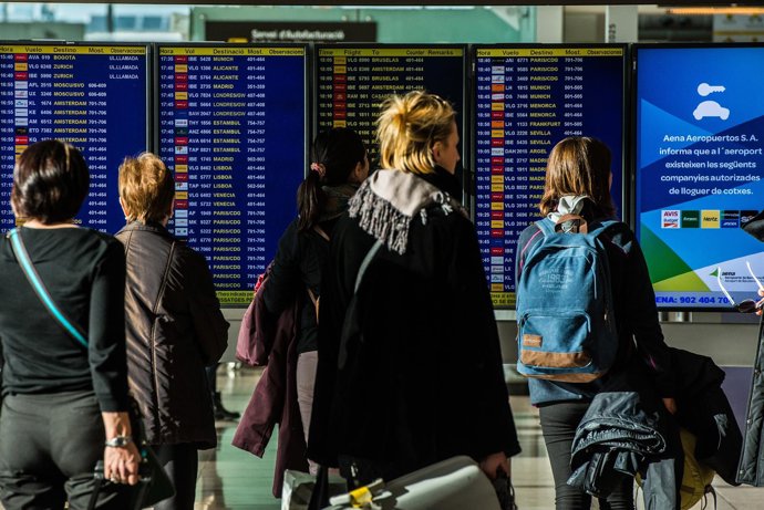 Gente mirando los paneles del aeropuerto