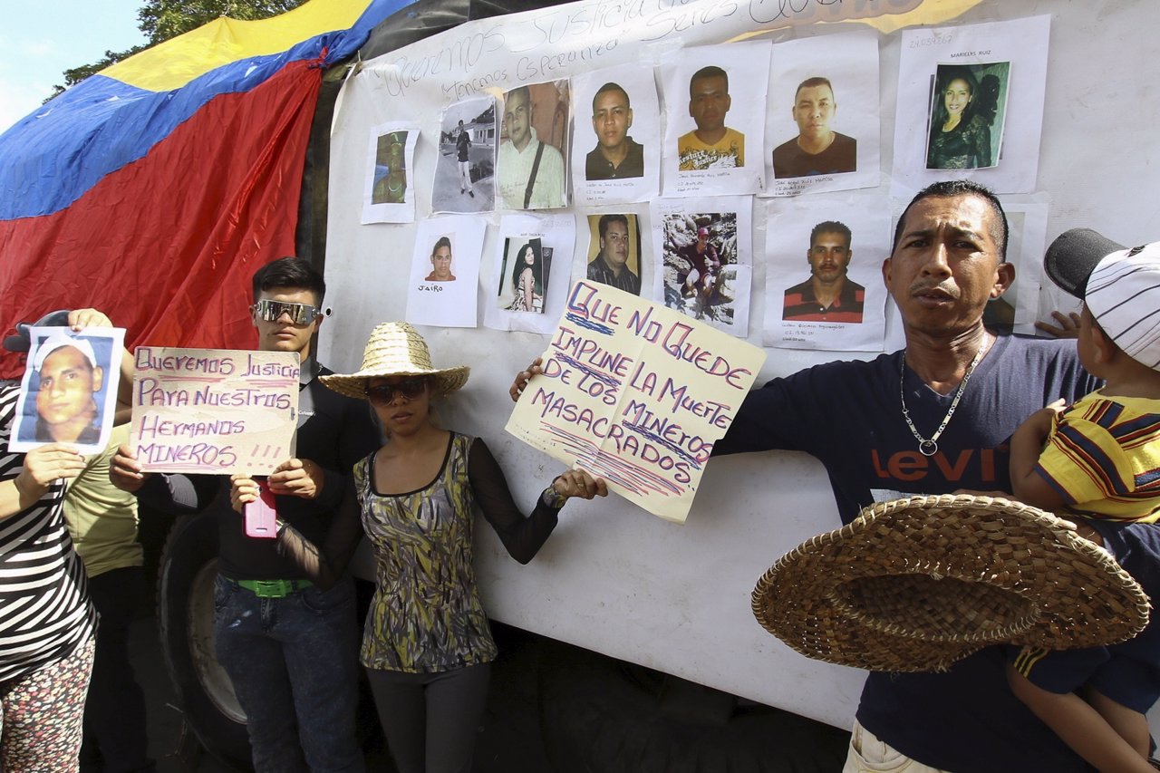 People hold placards in front of displayed pictures of missing miners during a d
