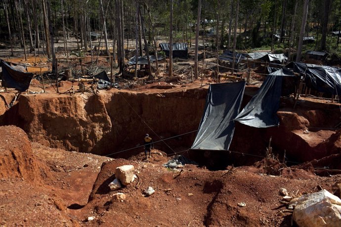 An illegal gold miner looks for gold at a makeshift camp for illegal mining near