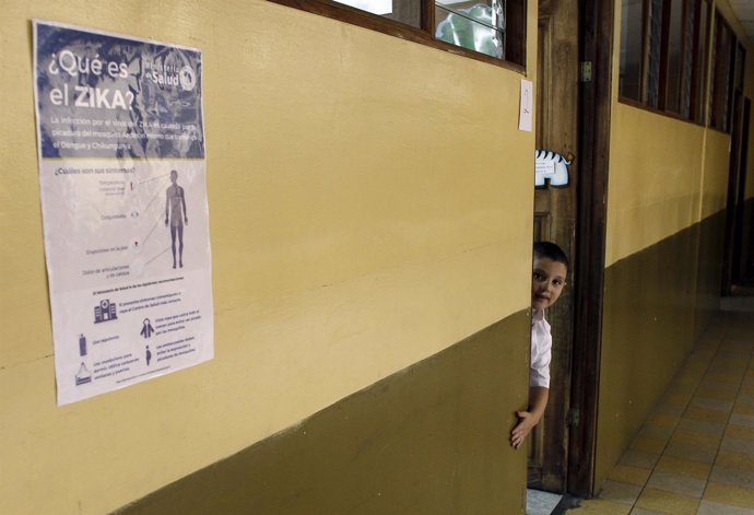 A boy looks out of his classroom near a poster informing the public of Zika viru