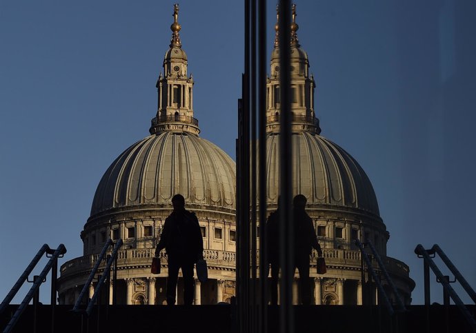 A worker descends steps near the Millenium Bridge, with St. Paul's Cathedral see
