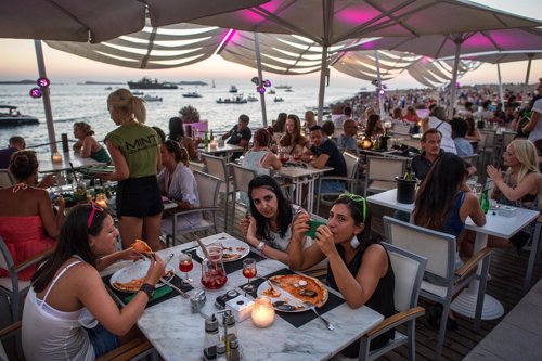 Gente comiendo en una terraza con vistas al mar
