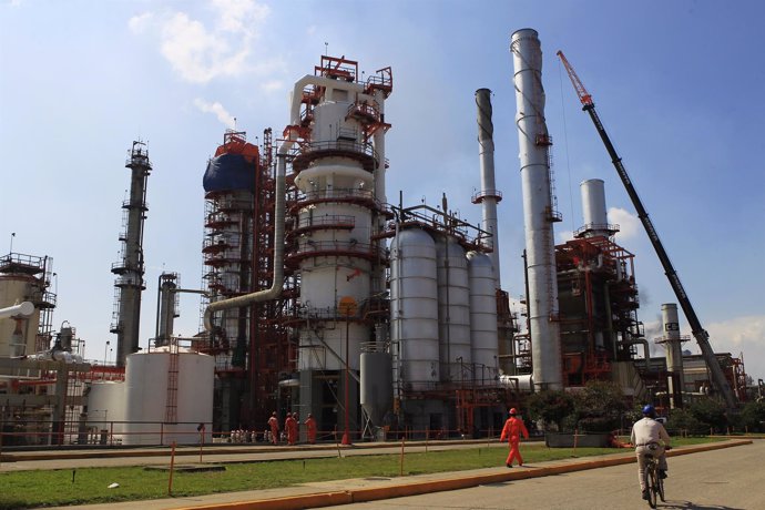 Refinery workers walk at one of the facility's catalytic plants, used to convert