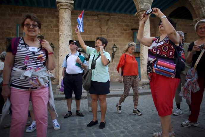 A tour guide raises a Cuban national flag to regroup foreign visitors she is tak