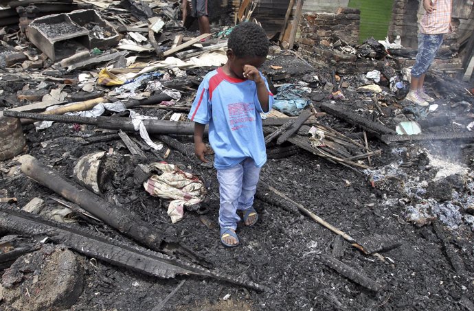 A child stands among the ruins of a house which was destroyed by a fire in a nei