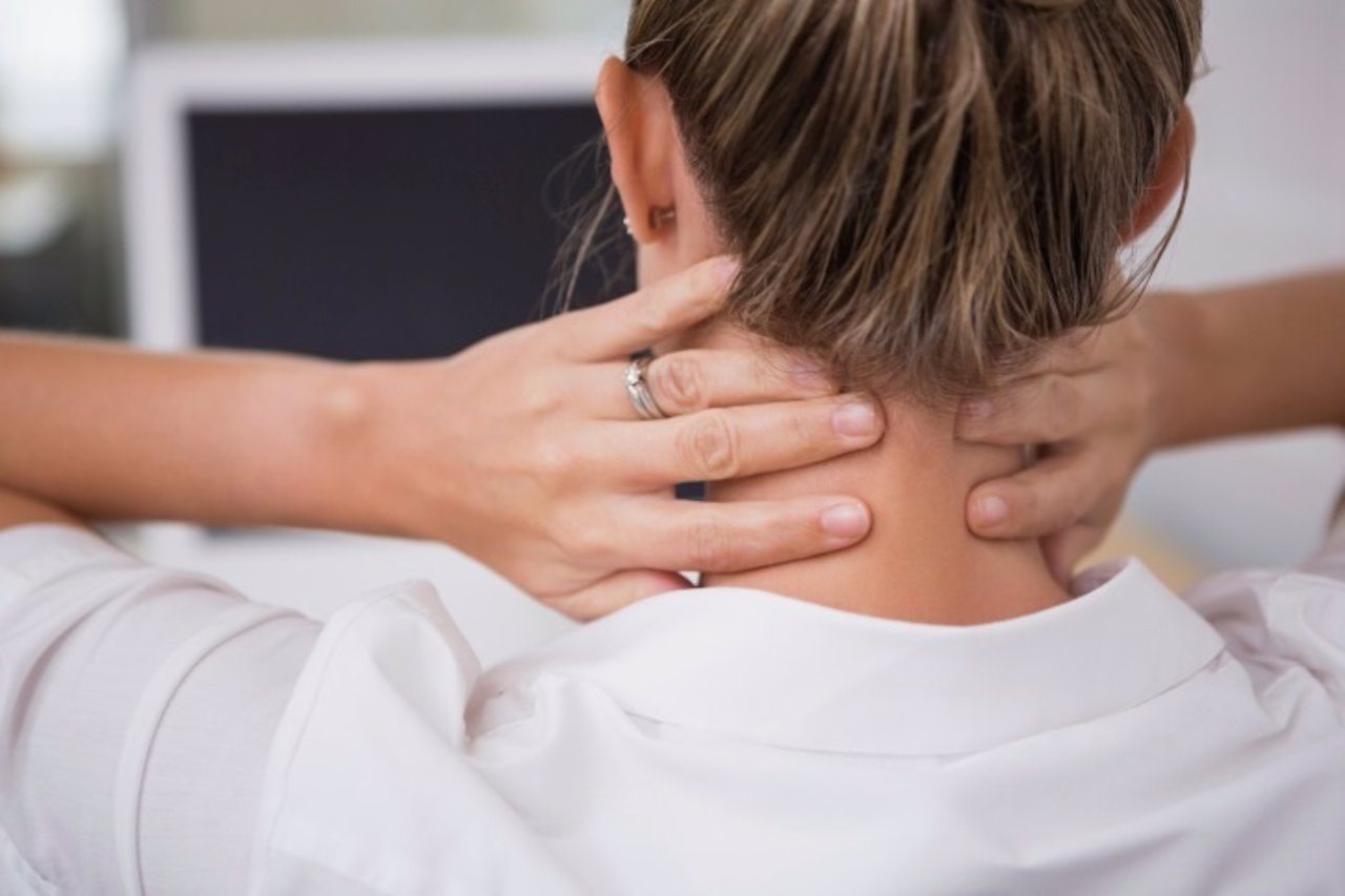 Mujer se masajea el cuello para aliviar su dolor.