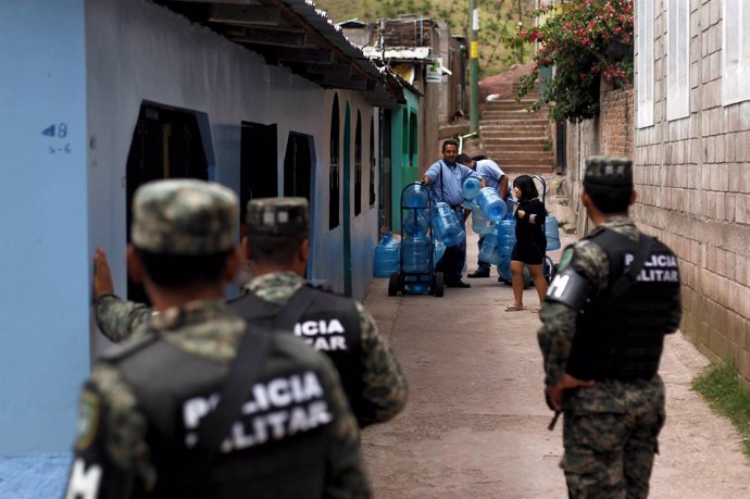 Members of the Military Police for Public Order (PMOP) look at a man distributin