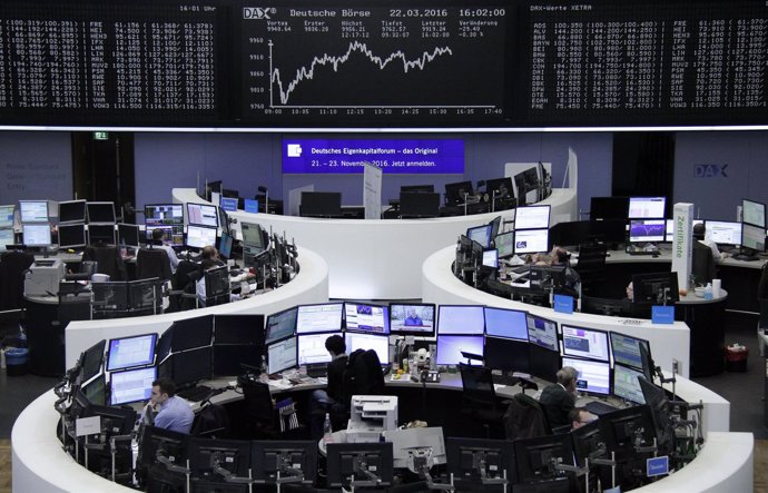 Traders work at their desks in front of DAX board at Frankfurt stock exchange