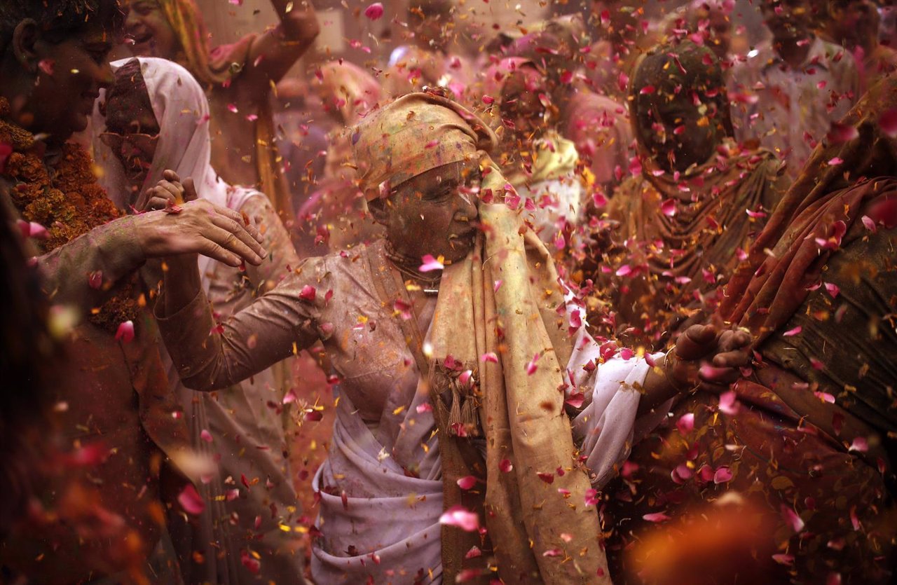 Widows daubed in colours dance as they take part in the Holi celebrations organi