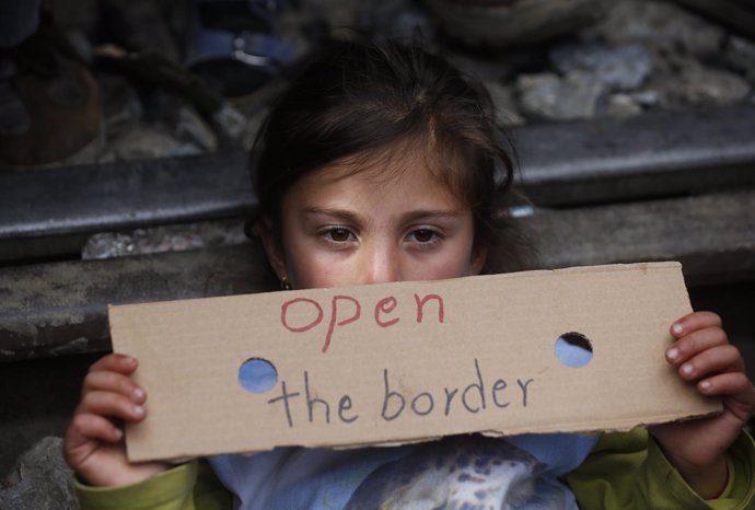 Niña refugiada muestra un cartel pidiendo la apertura de la frontera