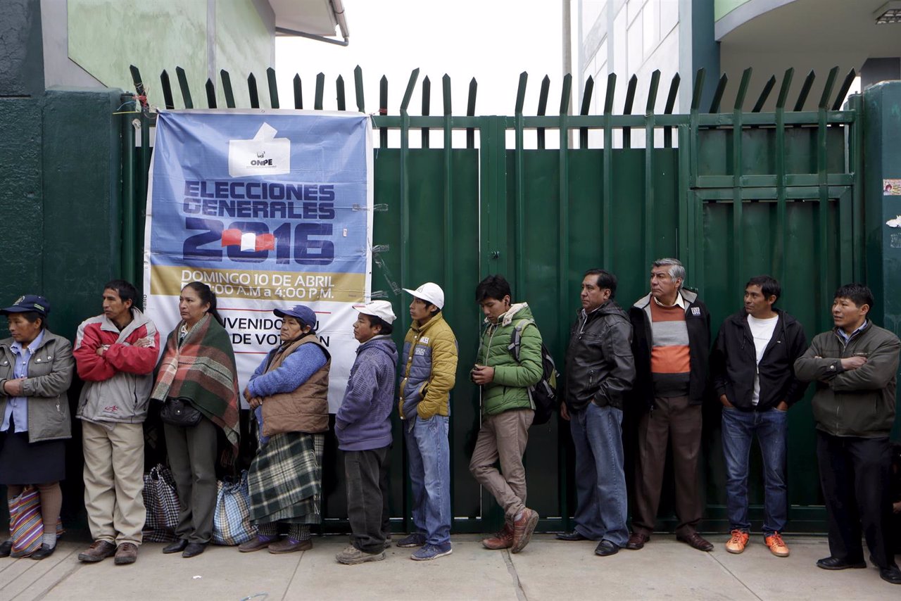 People waiting to vote stand in line outside a school before the start of the pr