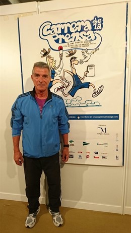EL humorista Manolo Sarria junto al cartel de la Carrera.