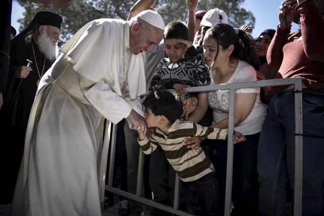 Handout photo of a boy shaking the hand of Pope Francis as he greets migrants an