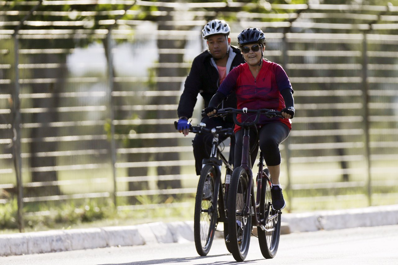 Brazil's President Dilma Rousseff rides her bicycle accompanied by bodyguard nea