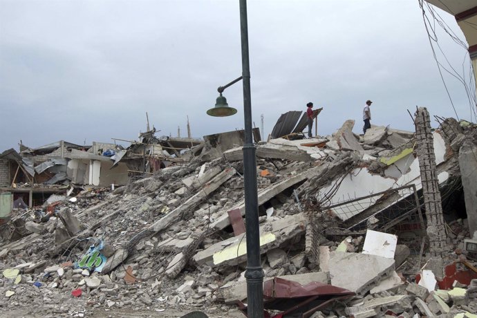 People look through debris as rescue efforts continue in Pedernales