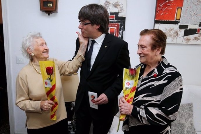 El presidente de la Generalitat, Carles Puigdemont, entrega rosas a dos ancianas