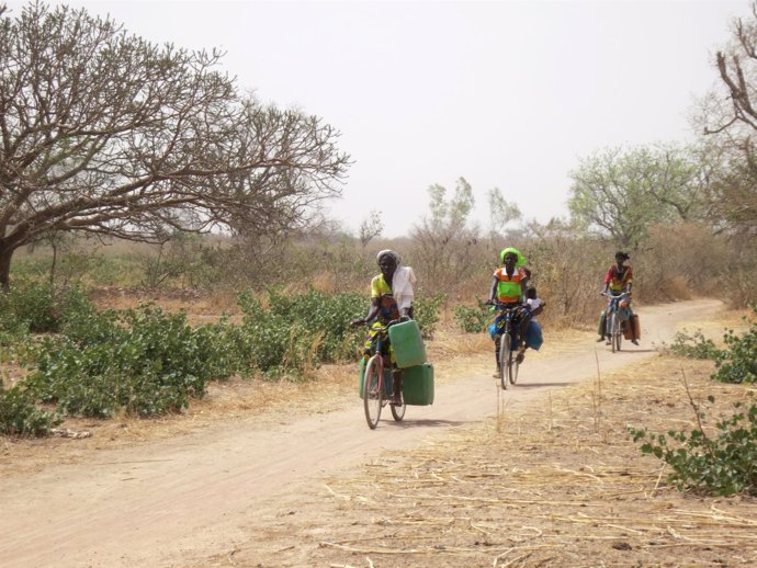 Mujeres transportando agua en bicicletas en Burkina Faso