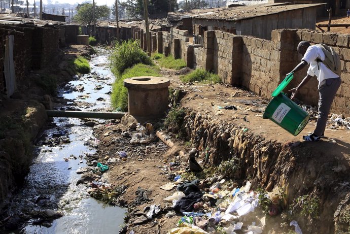 A student empties a dustbin next to a murky stream near a school in Kenya's Kibe