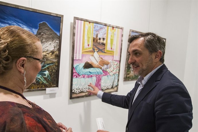 El diputado Ángel Escobar conversa sobre los cuadros con Isabel Toresano.