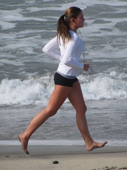 Mujer corriendo descalza por la playa