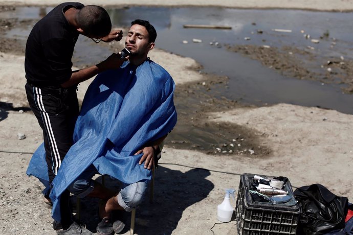 Un refugiado le corta el pelo a otro en Idomeni