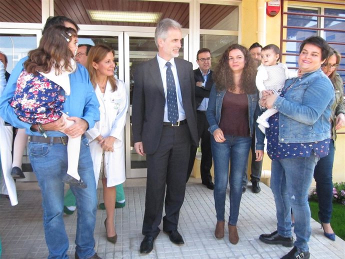 El consejero (centro) mira a la bebé, sostenida por su madre, junto a su tía