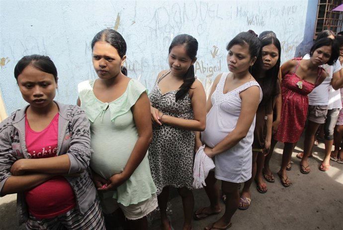 Pregnant teenagers queue for a free pre-natal check-up during a medical mission 