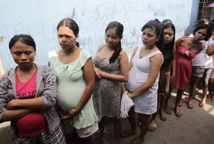 Pregnant teenagers queue for a free pre-natal check-up during a medical mission 