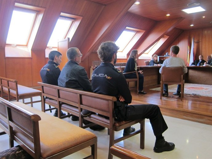 El acusado de violar a una amiga en el juicio contra él, flanqueado por policías