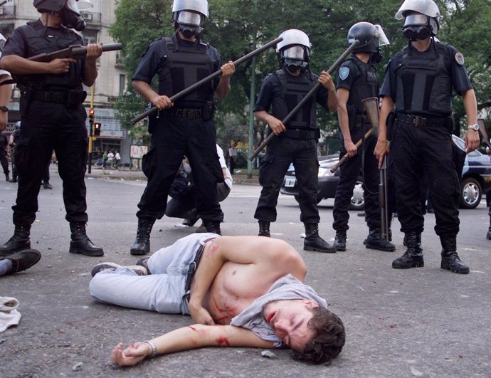 Policía mirando manifestante en represión Argentina 2001