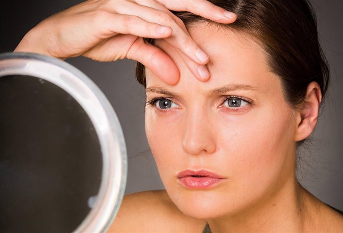 Woman checking her face in the mirror.