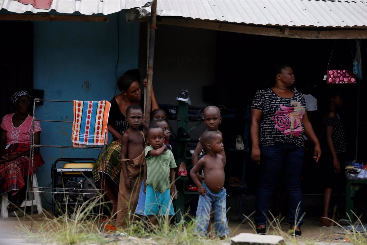 Children are seen standing in front of a house along Marine Field Street in Goka