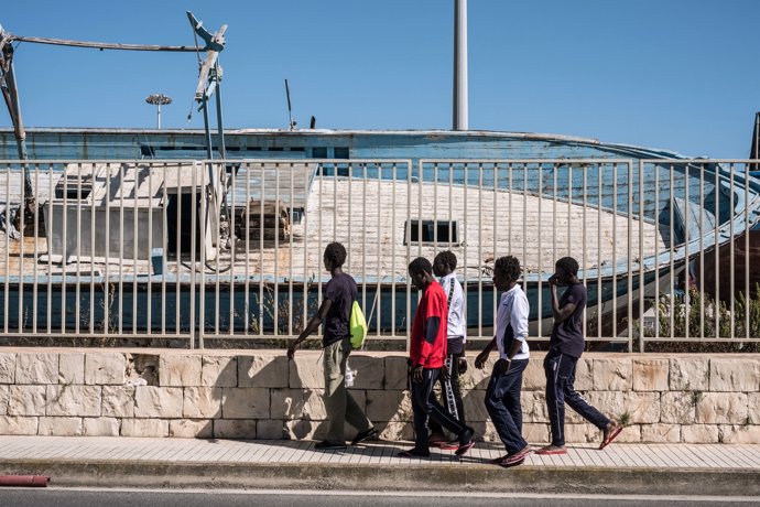 Menores gambianos frente a un cementerio de barcos en Libia