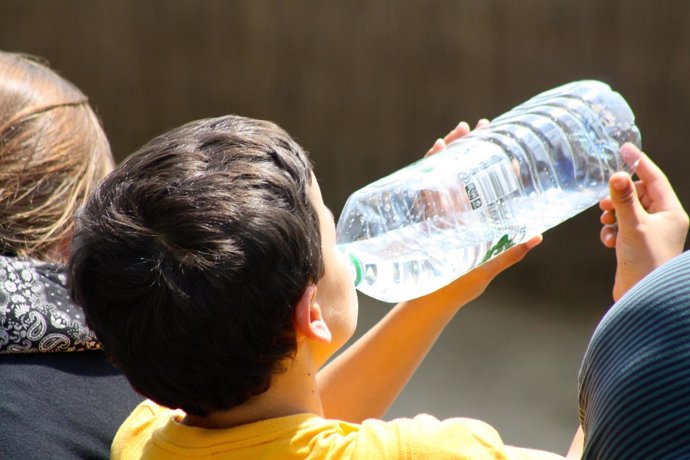Un niño bebe agua en una botella