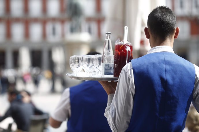 Un camarero sirve bebidas en una terraza