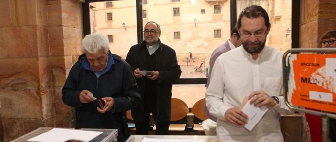 Emilio León vota, con el Arzobispo de Oviedo detrás